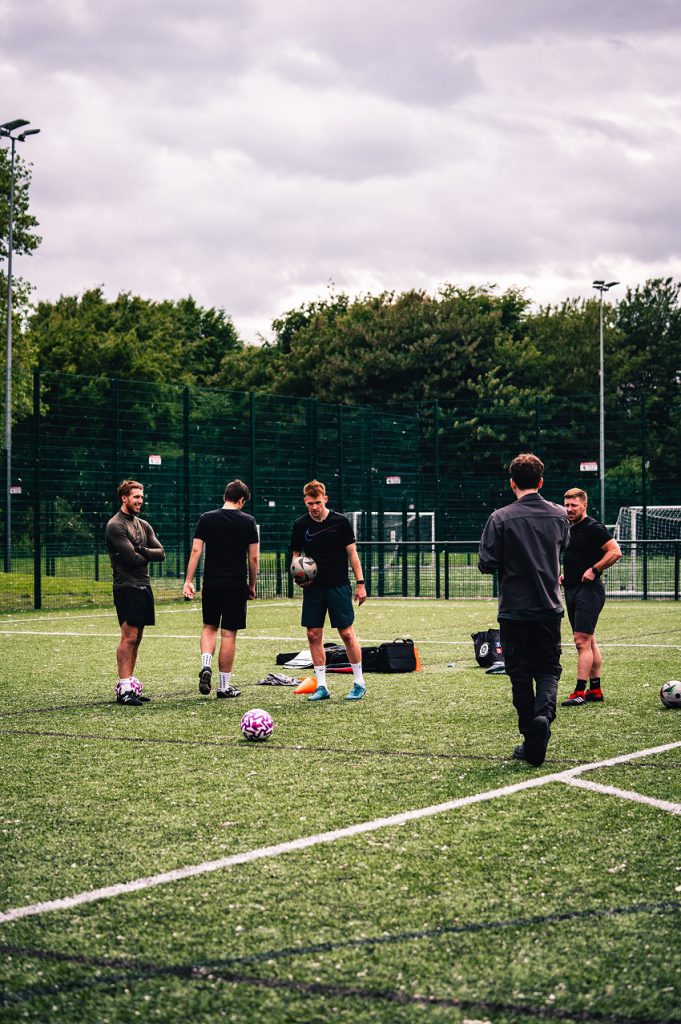 A group of men stood talking during a football training session